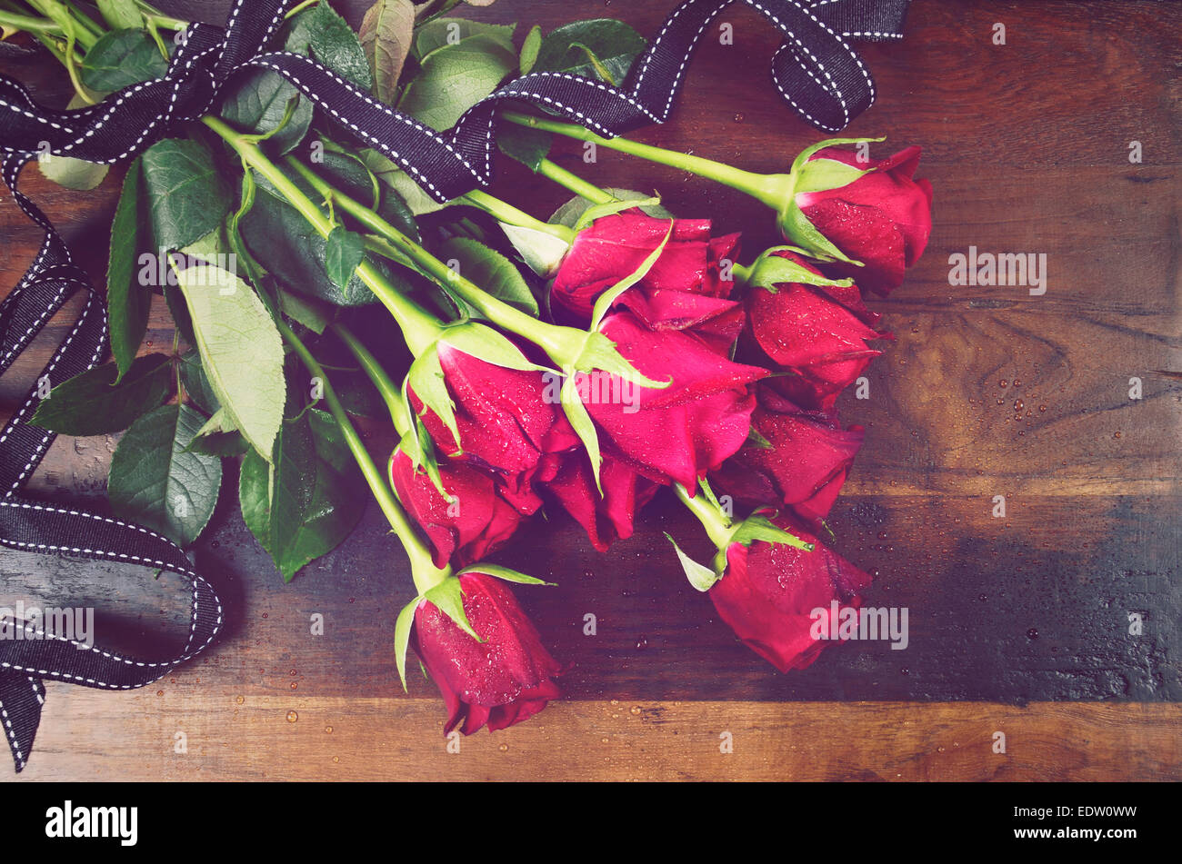 Retro Vintage Valentinstag rote Rosen auf dunkle recycelt Holz Hintergrund - overhead mit schwarzen Band. Stockfoto