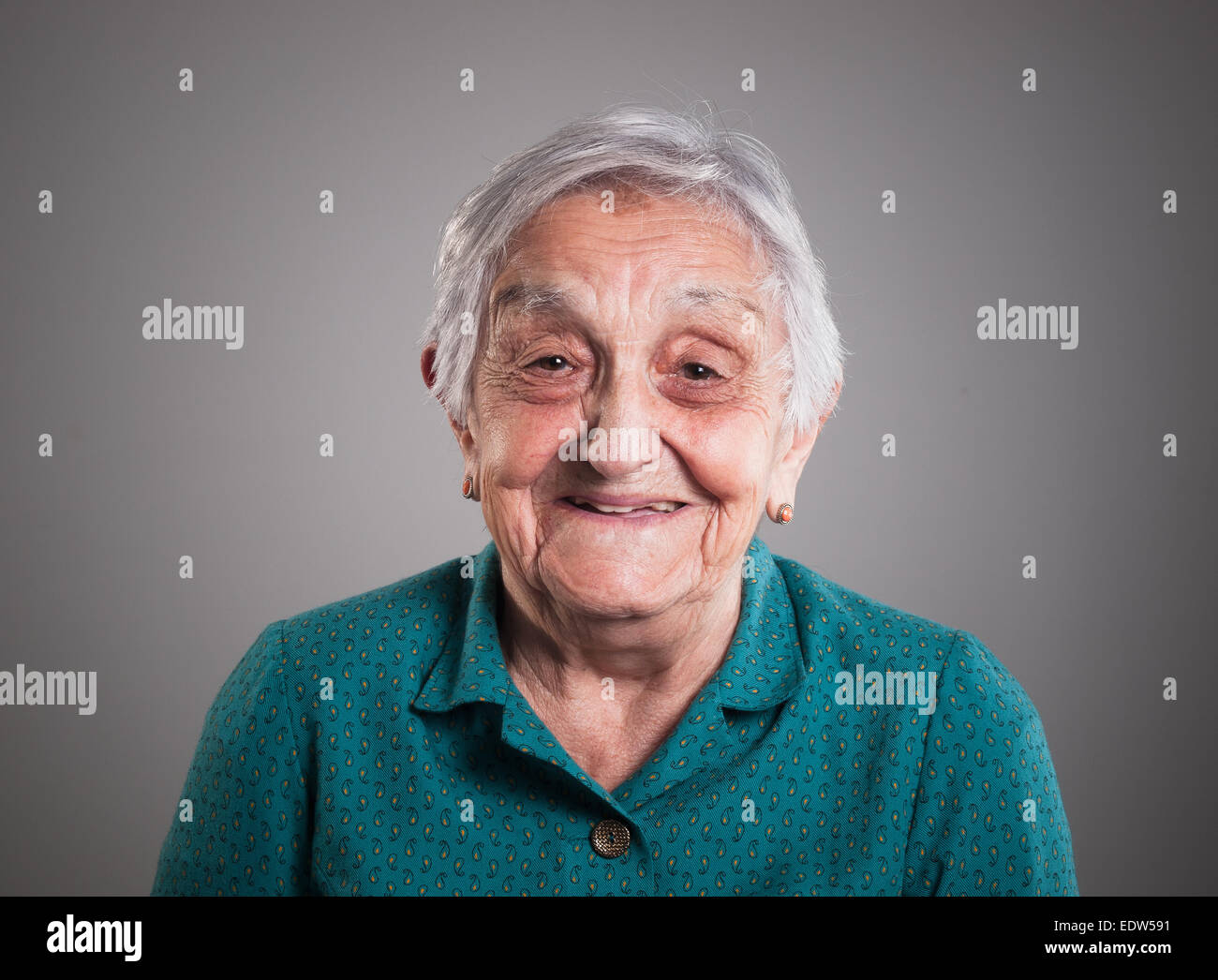 Oma glücklich und lächelnd isoliert auf grauem Hintergrund Stockfoto