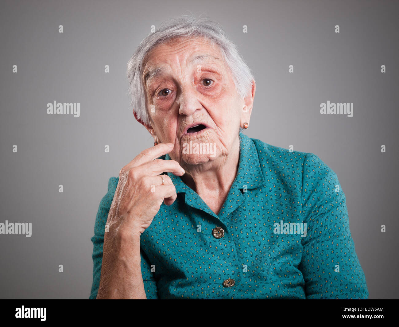 Ältere Frau mit Ausdruck überrascht und isoliert auf dunklem Hintergrund Stockfoto