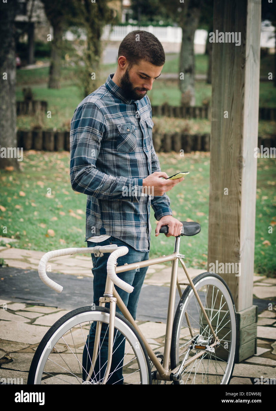 Hipster-Mann mit einem Fixie Fahrrad und Smartphone in einem Park im freien Stockfoto