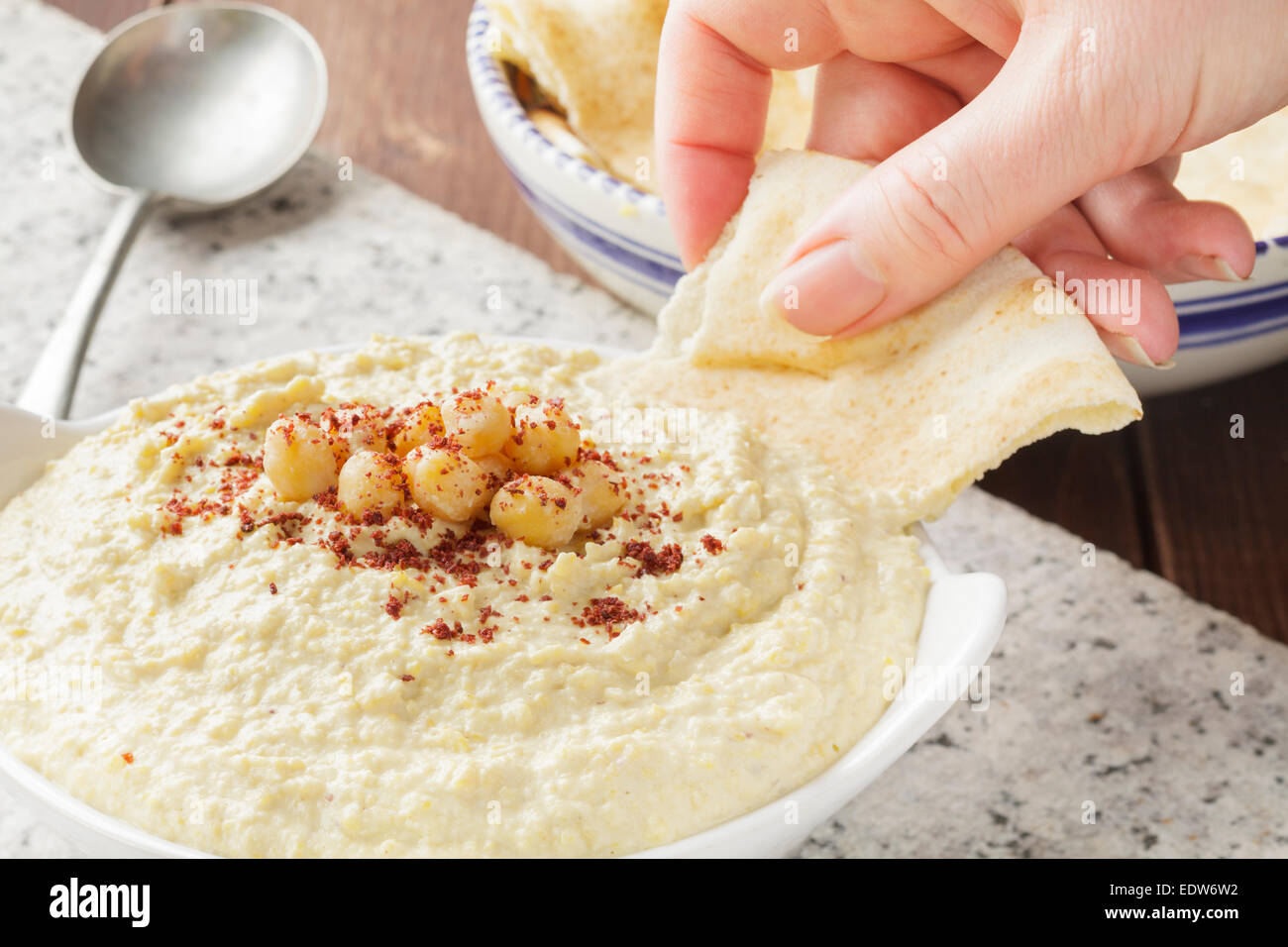 Fladenbrot in Hummus Dippen Hand Stockfoto