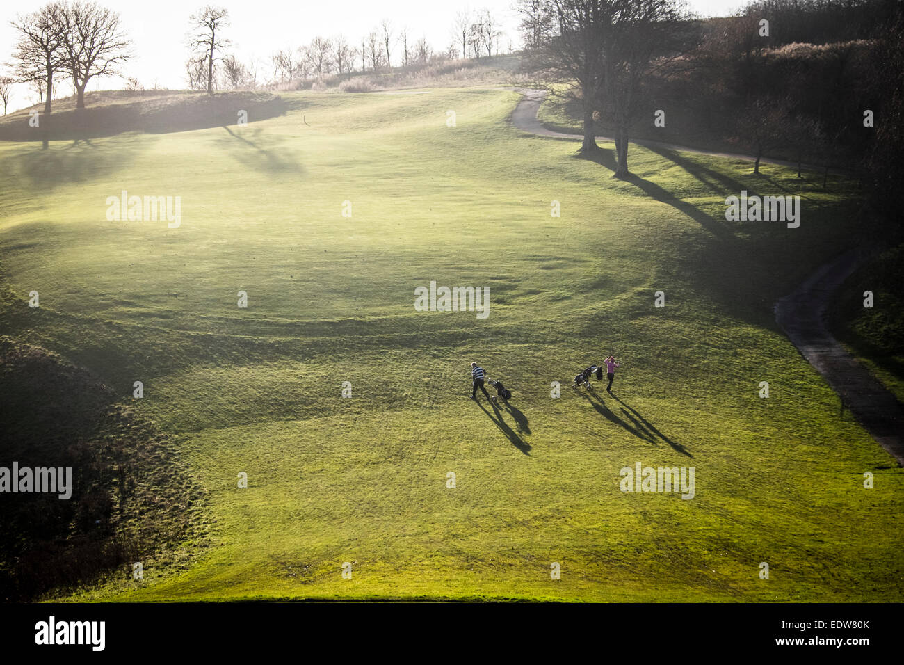 Zwei Golfer auf dem Celtic Manor Resort, eine Fahrrinne mit langen Abend Schatten hinaufzugehen. Stockfoto