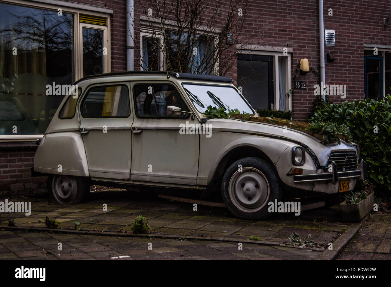 Citroen 2CV geparkt vor einem Haus mit Blumen wachsen aus dem Motor Bucht in Nijmegen, Nederland Stockfoto