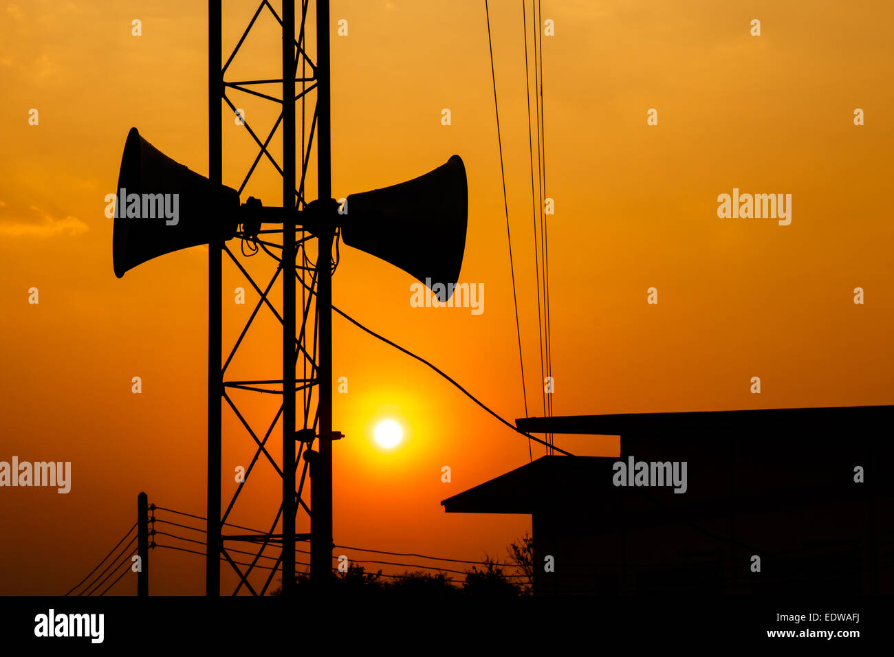 Lautsprecher auf Metall Säule über dem Dach des Hauses in der Dämmerung Zeit in Thailand (Silhouette-Stil) Stockfoto