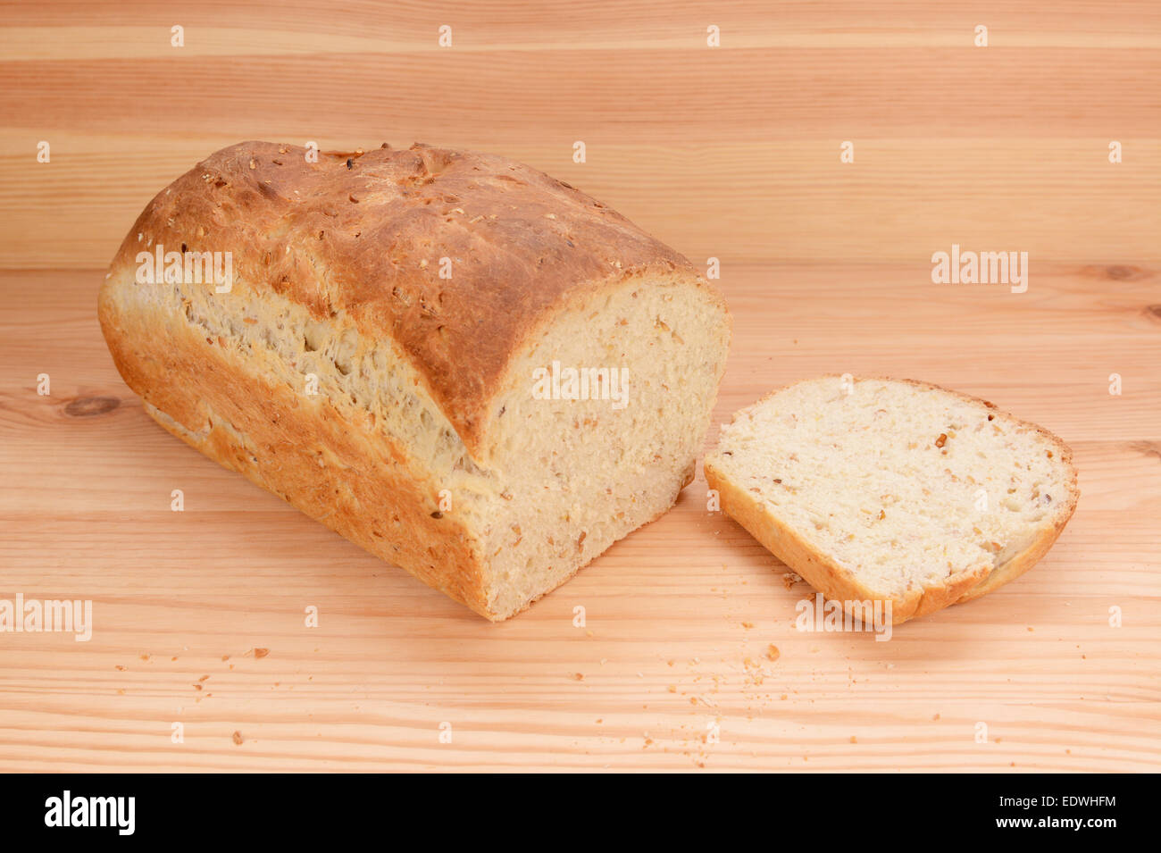 Schneiden Sie Scheibe von einem frisch gebackenen Laib Hafer und Leinsamen Brot auf einem Küchentisch Stockfoto