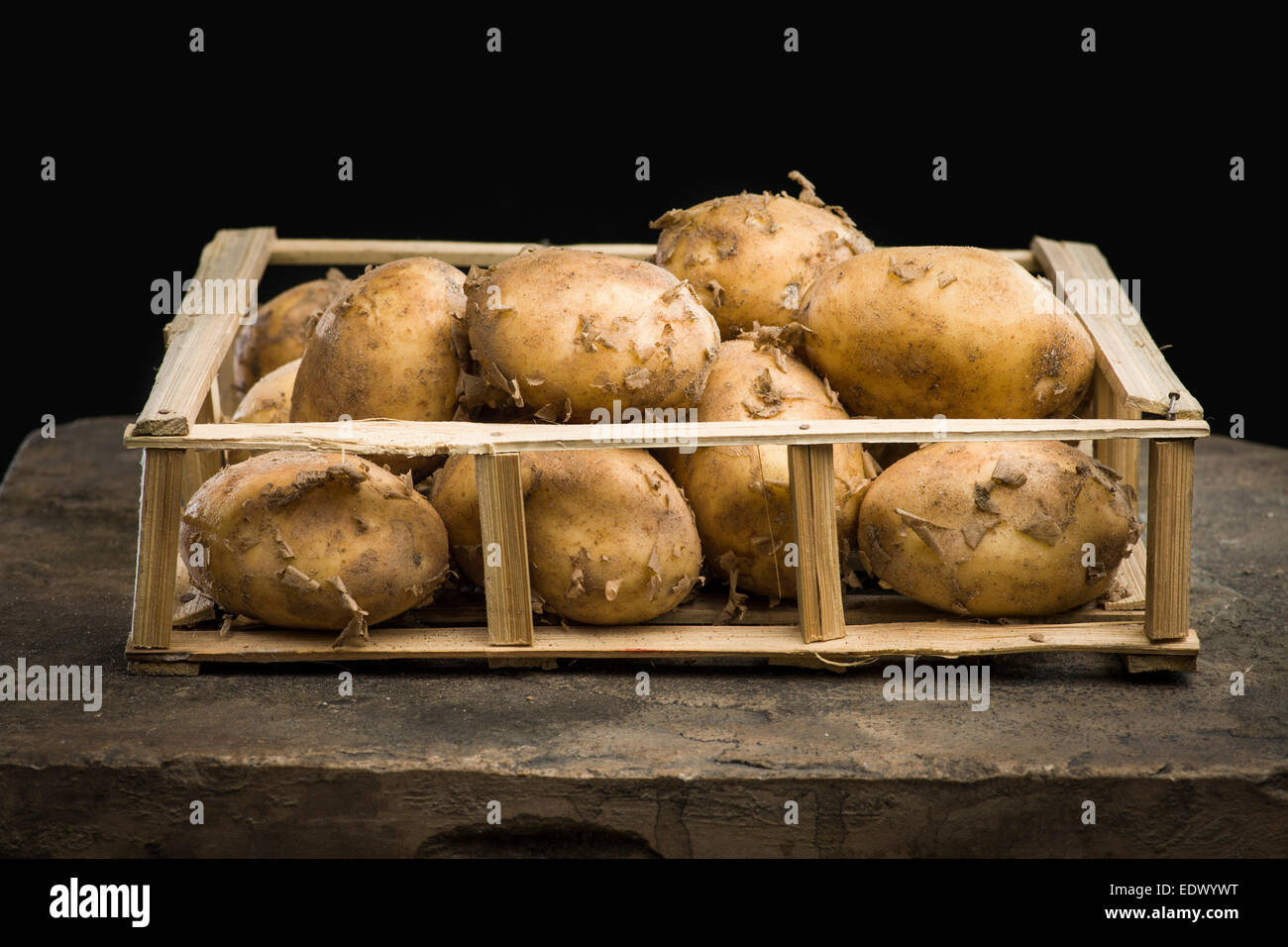 Junge Reife Kartoffeln in einer Holzkiste auf dem dunklen Hintergrund Stockfoto
