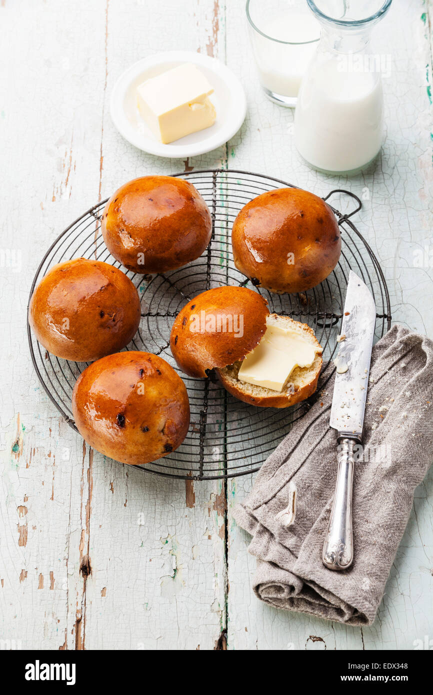 Hausgemachte Brötchen mit Rosinen auf Kuchengitter abkühlen auf blauem Hintergrund aus Holz Stockfoto