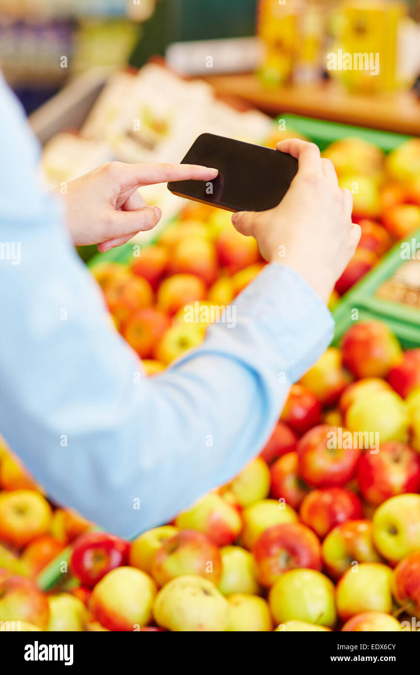 Hand, Scannen Informationen von frischem Obst mit einem Smartphone in einem Supermarkt Stockfoto
