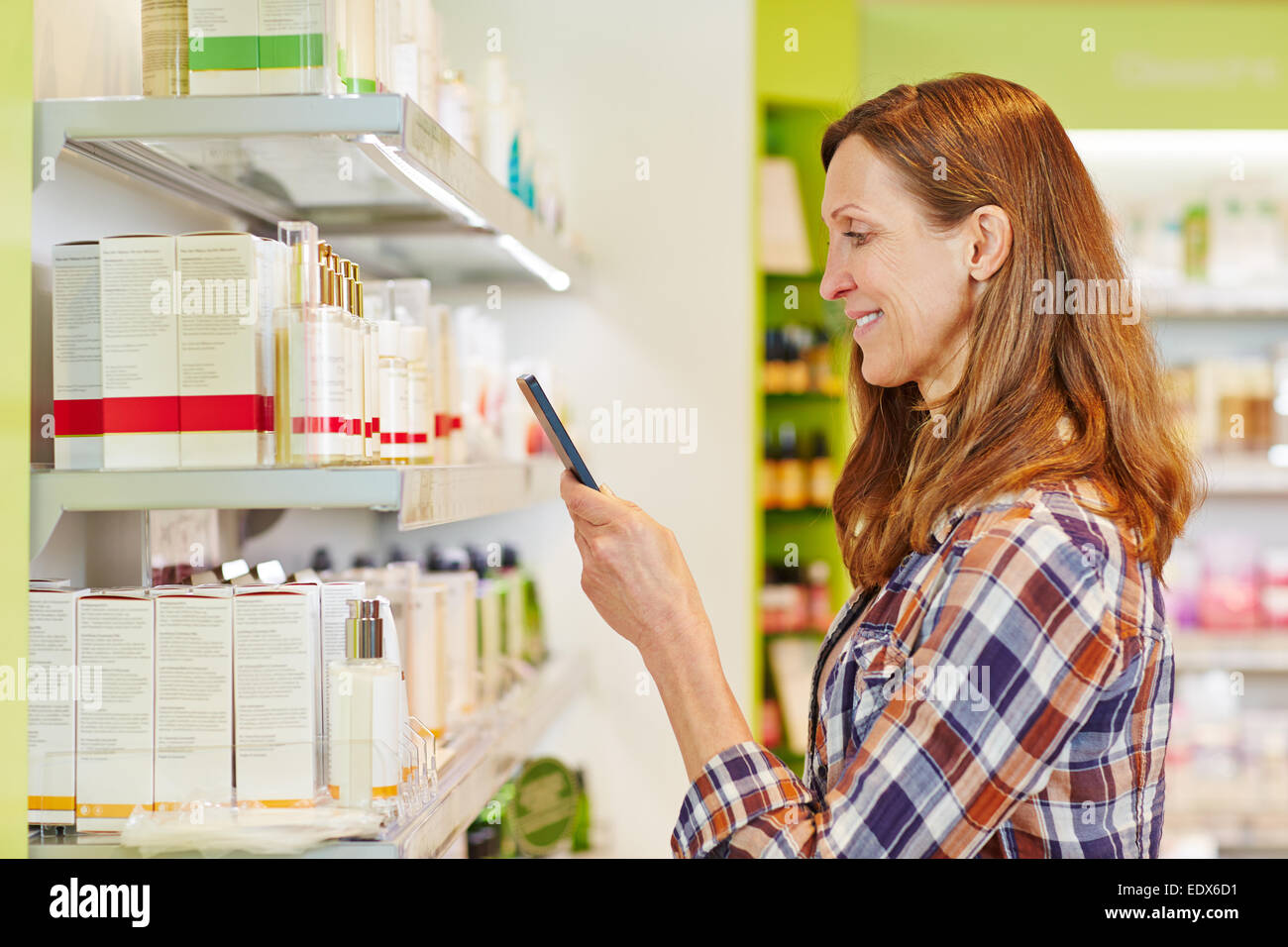 Frau Barcode Kosmetik im Supermarkt mit ihrem Smartphone Scannen Stockfoto