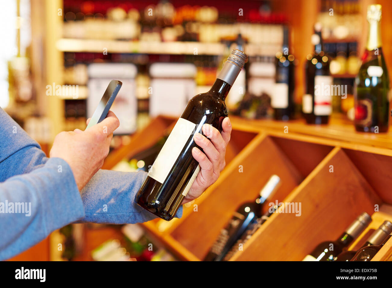 Hand mit Smartphone Scannen Flasche Wein im Supermarkt für Preisvergleich Stockfoto