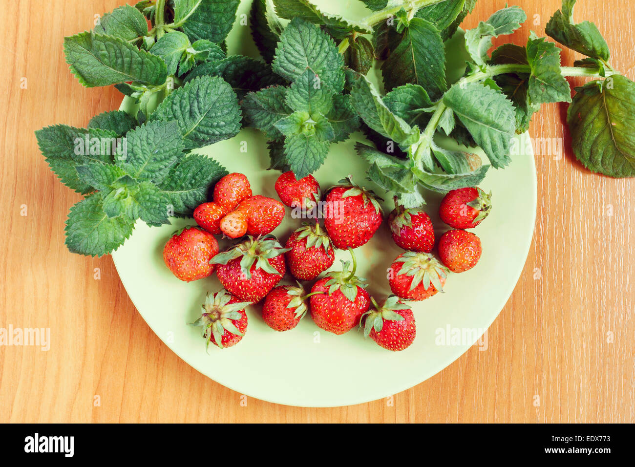 Erdbeeren und Minze Blätter auf Teller grün Stockfoto