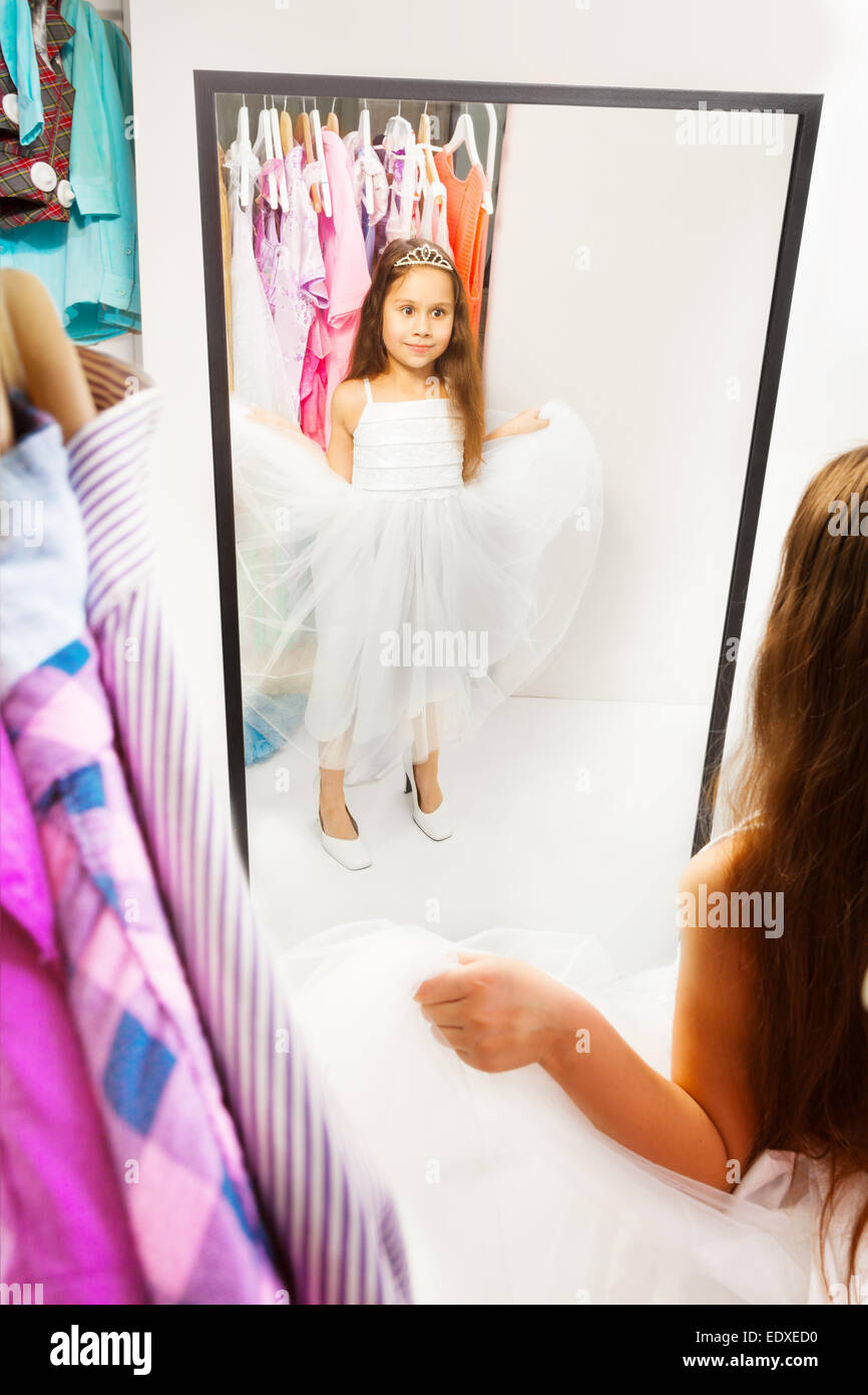 Wunderschönes kleines Mädchen versuchen Kleid vor dem Spiegel Stockfoto