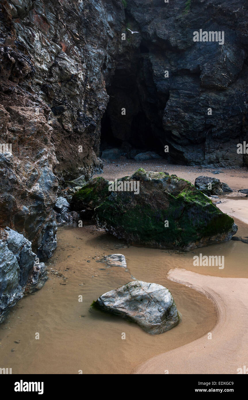 Interessante Geologie in den Felsen am Strand von Perranporth in Cornwall. Ein Felsenpool und dunkle Höhle. Stockfoto