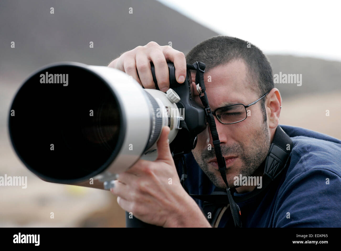 Fotografen mit Brille verwendet ein Canon-Teleobjektiv Stockfoto