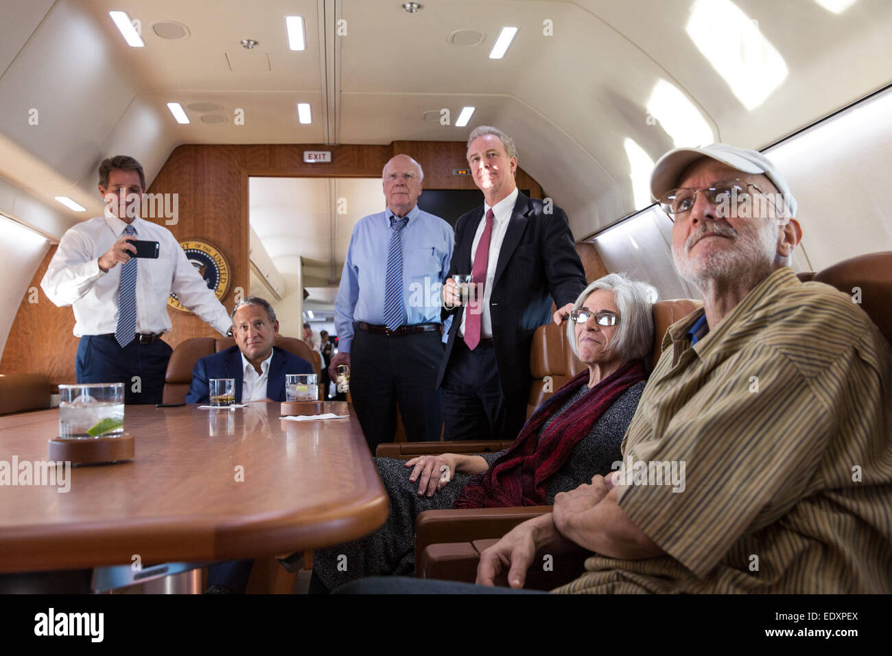 Alan Gross mit seiner Frau Judy, Anwalt Scott Gilbert, Rep, Chris Van Hollen, D-MD., Senator Patrick Leahy, D -VT und Senator Jeff Flake, R -ARIZ Fernsehen an Bord eine Regierung Flugzeug zurück in die USA als die Nachrichten bricht seine Freilassung, 17. Dezember 2014 geleitet. Stockfoto