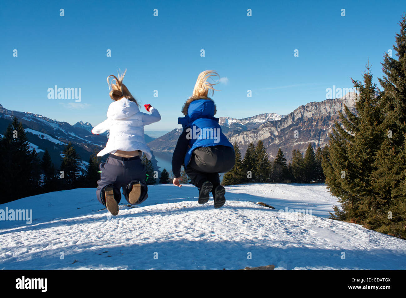zwei Teenager blonden Haaren in die Luft springen auf einen Skiurlaub in der Schweiz Stockfoto