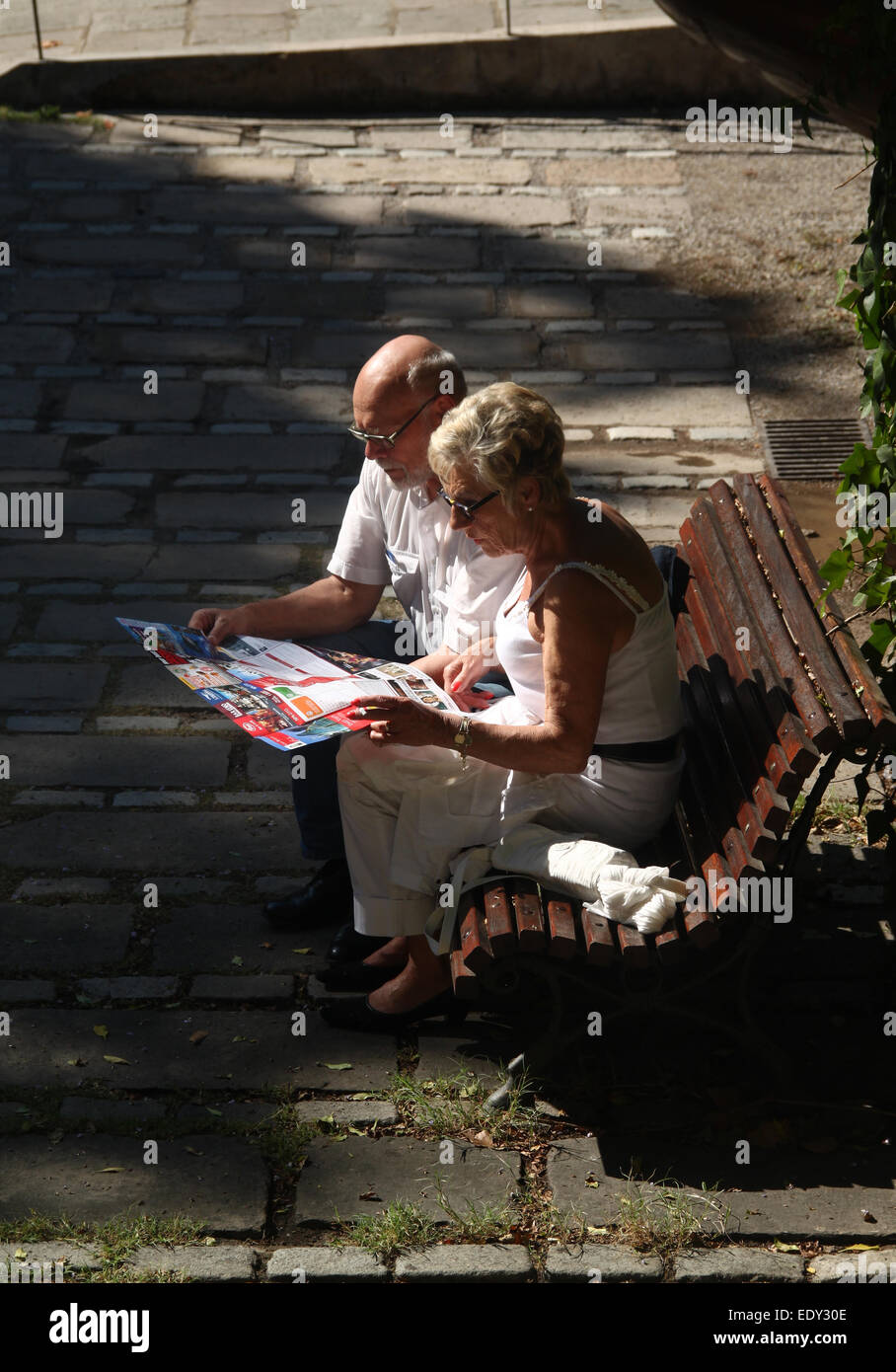 Touristen-paar auf der Suche auf Karte, sitzen auf der Bank im Garten außerhalb Maritime Museum, abseits der Ramblas in Barcelona. Stockfoto