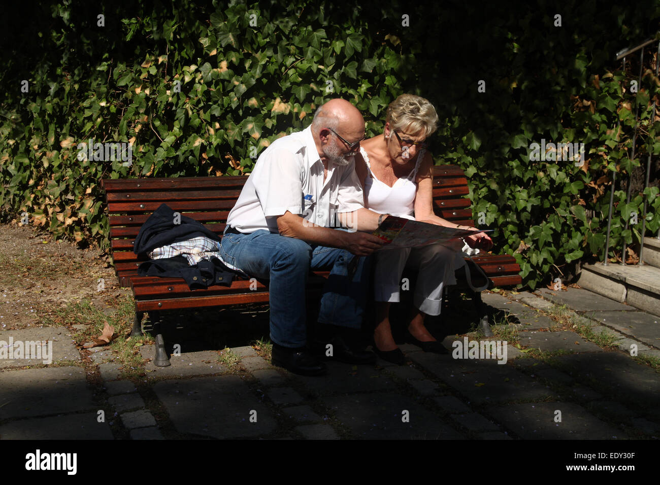 Touristen-paar auf der Suche auf Karte, sitzen auf der Bank im Garten  außerhalb Maritime Museum, abseits der Ramblas in Barcelona Stockfotografie  - Alamy