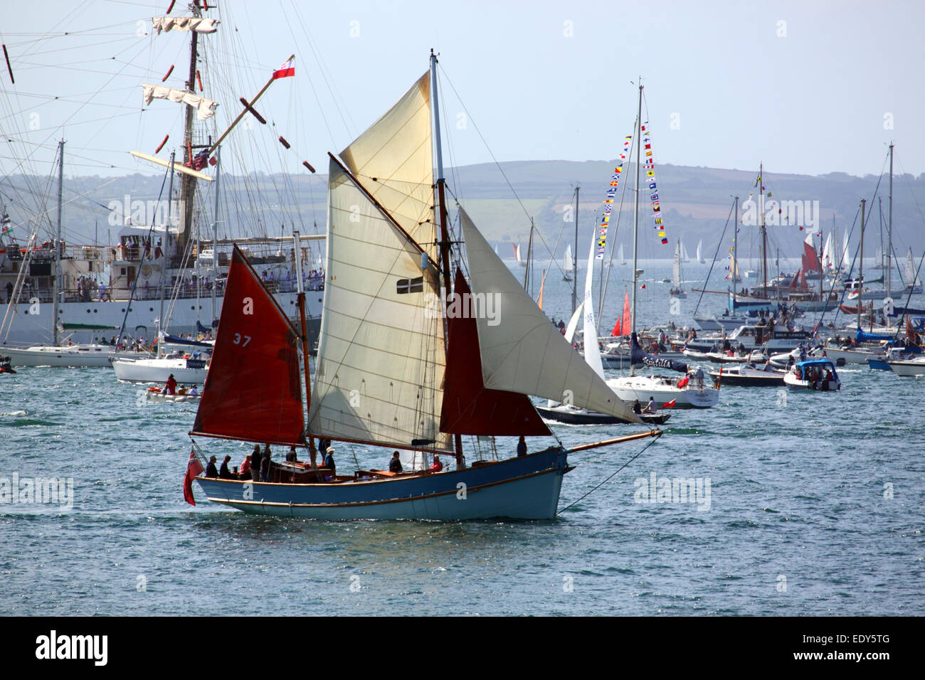 Ein Gaff rigged Yawl mit einem Cornish Flagge inmitten einer Schar von anderen Booten. Stockfoto