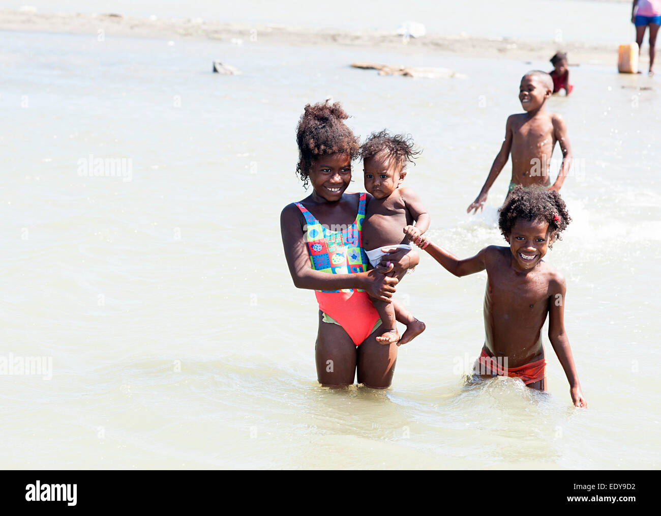 Große Schwester und Geschwister aus nahe gelegenen armen Dorf hält stolz Baby für Foto in das Karibische Meer in der Nähe von Cartagena Kolumbien Stockfoto