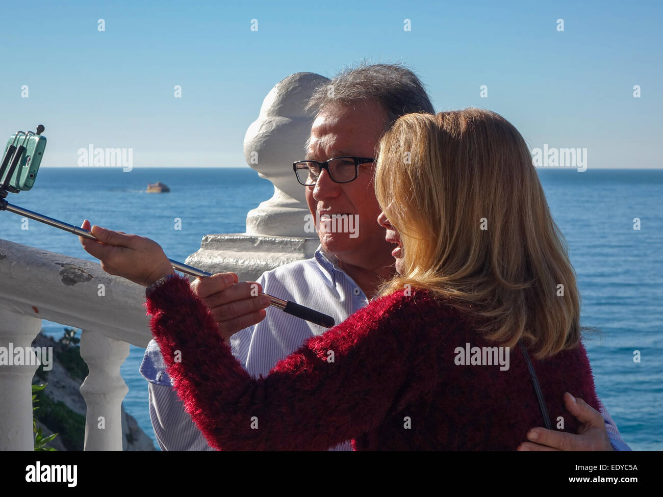 Älteres paar unter selfy per Selfie-Stick und Handy, Handy-Bild an sonnigen Tag am Meer in Benidorm. Stockfoto