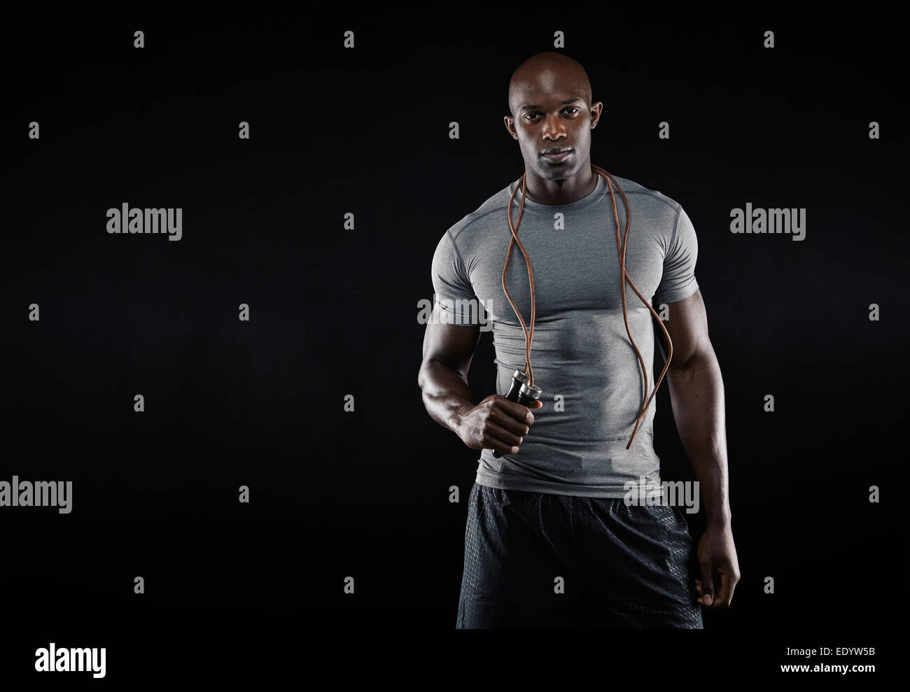Studioaufnahme des jungen afrikanischen muskulöser Mann mit Seilspringen auf schwarzem Hintergrund. Fitness-Modell mit Seilspringen. Stockfoto