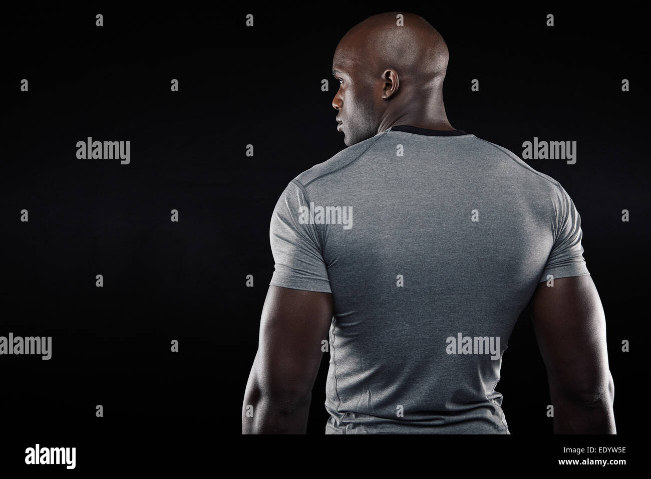 Rückansicht des Fit junger Mann muskulös steht auf schwarzem Hintergrund. Afro American Fitness-Modell im Studio. Stockfoto