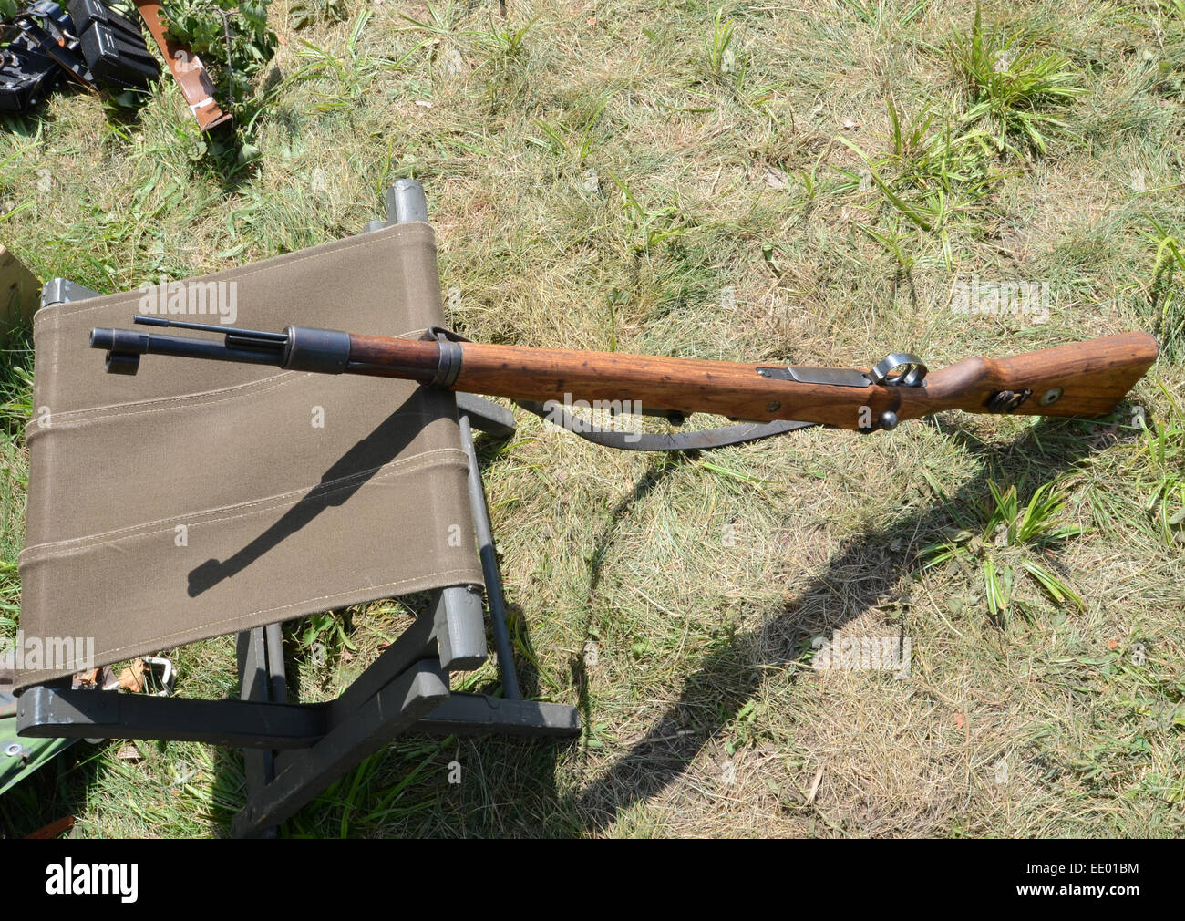 Alte Waffe auf dem Boden gegen Stuhl aus dem 2. Weltkrieg Stockfoto