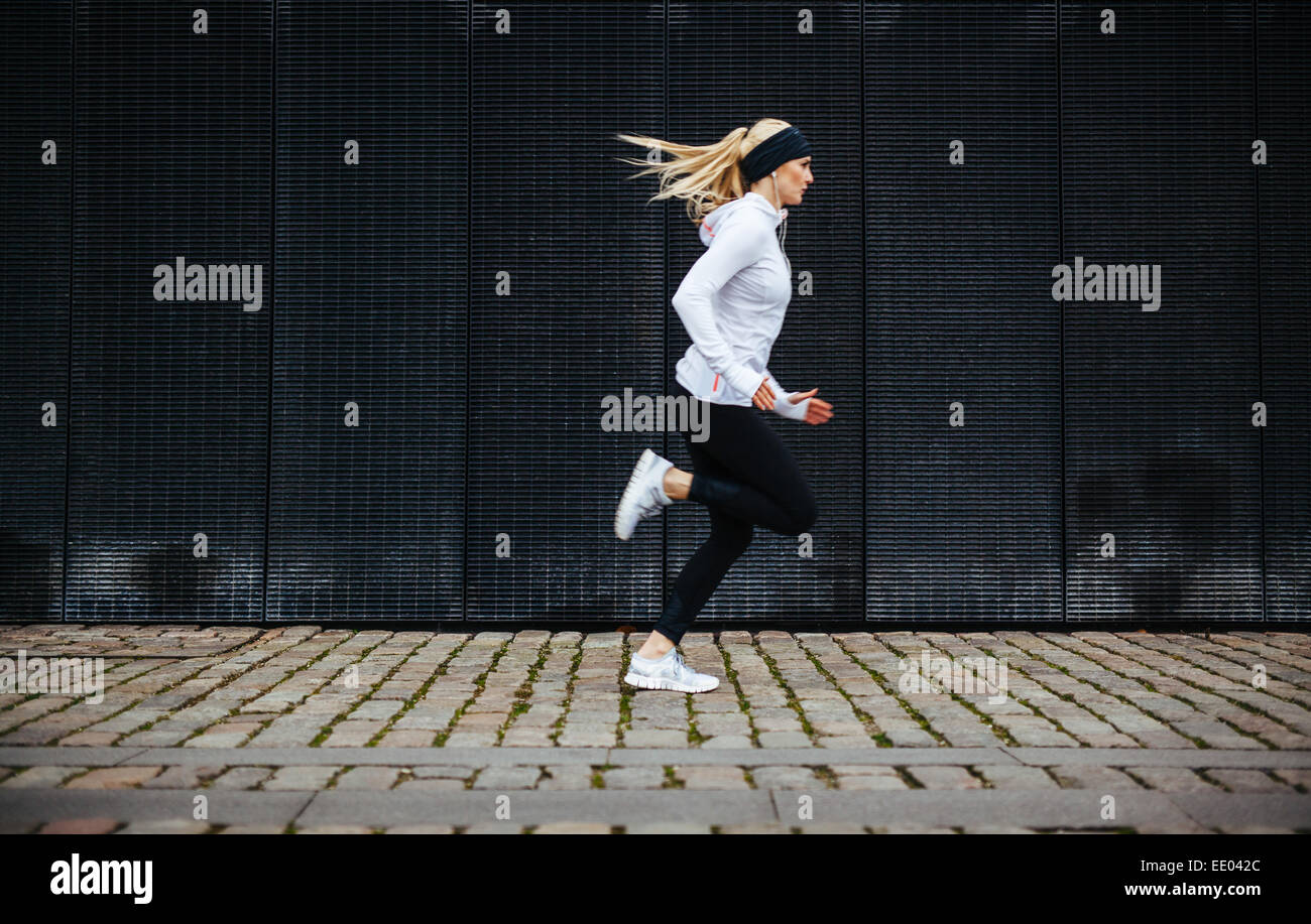 Seitenansicht der sportliche junge Frau auf Bürgersteig morgen ausgeführt. Bewusste Gesundheitskonzept mit Textfreiraum. Stockfoto