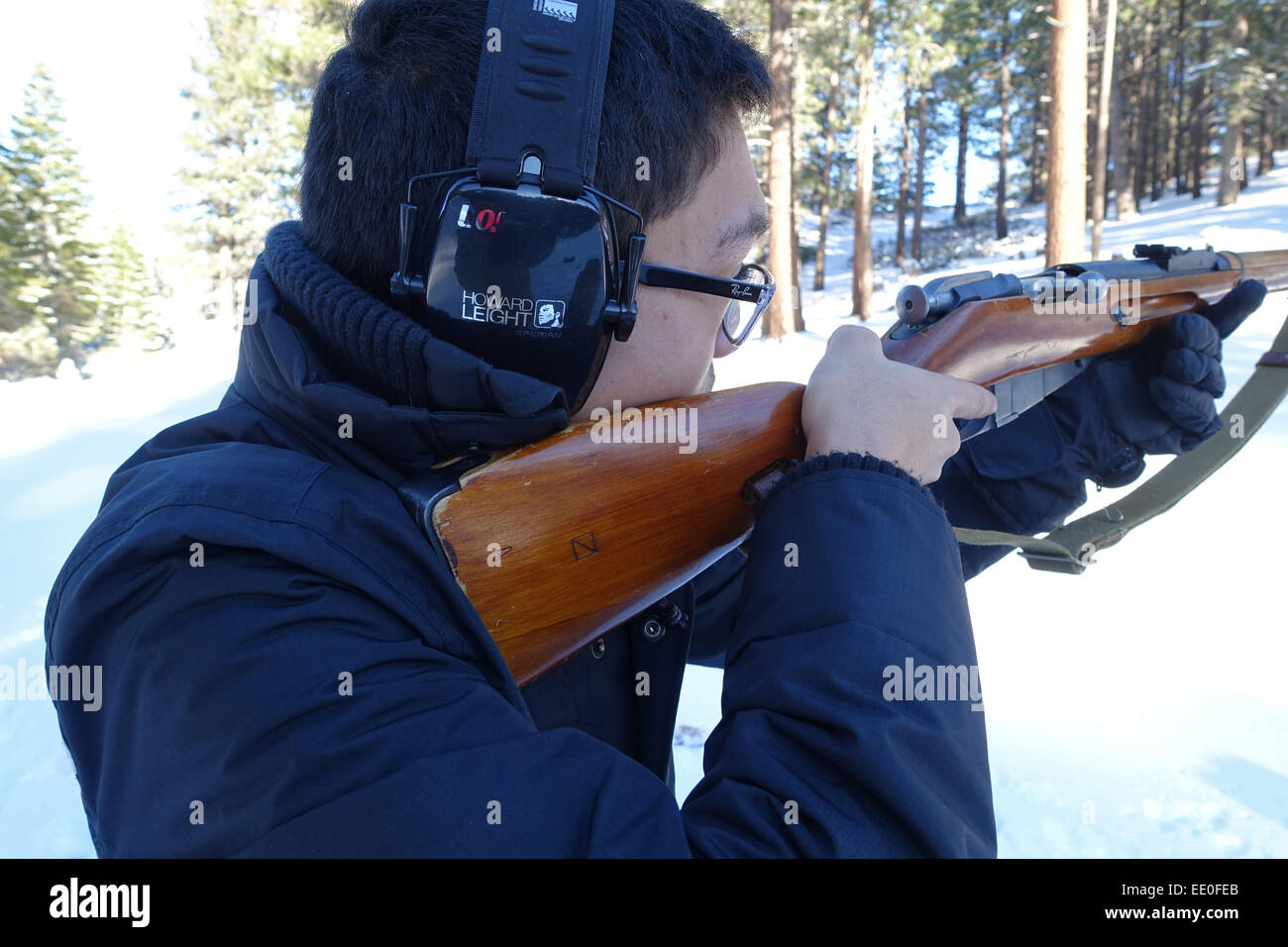 USA A Asian American Teen Mann schießt einen russischen gemacht Mosin Repetierbüchse in der verschneiten Wildnis von Nevada NV Stockfoto