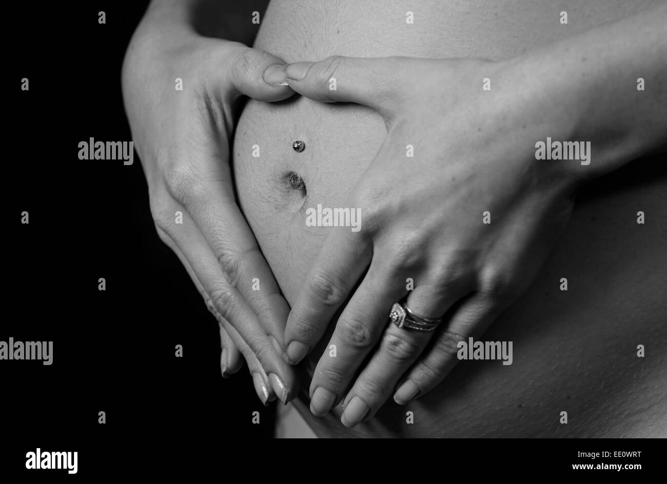 Eine Frau hält ihre Hände auf ihren Bauch oder Beule während schwangere erstellen eine Herzform als Symbol für Liebe. Stockfoto