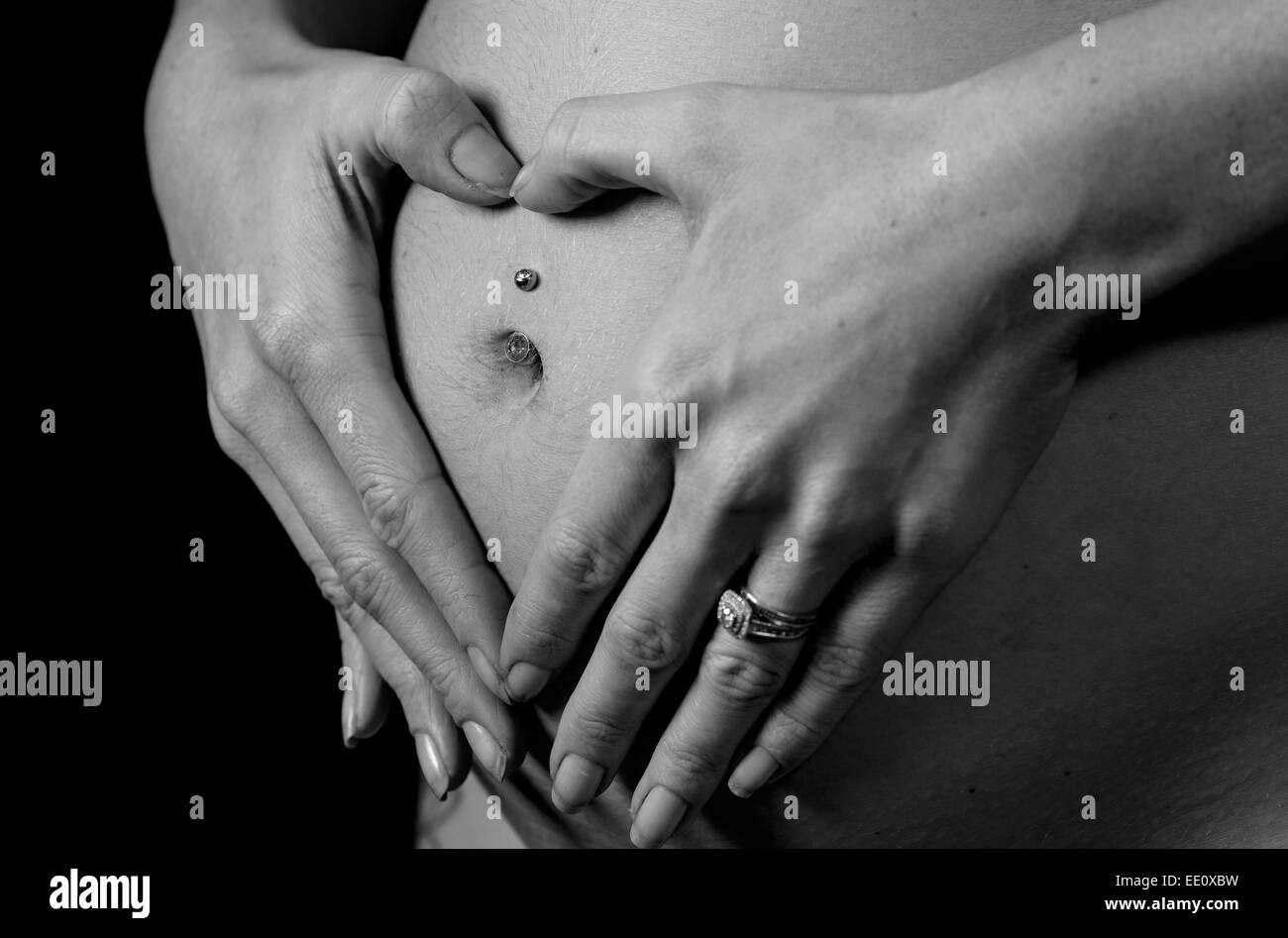 Eine Frau hält ihre Hände auf ihren Bauch oder Beule während schwangere erstellen eine Herzform als Symbol für Liebe. Stockfoto