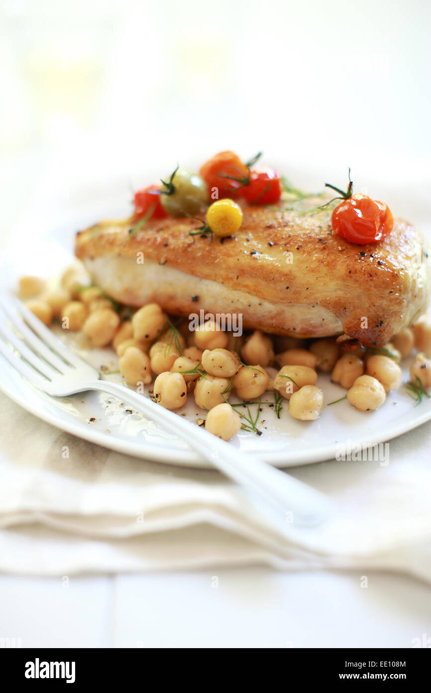 Bio-Huhn mit gebratenen Tomaten und Kichererbsen geröstet. Stockfoto