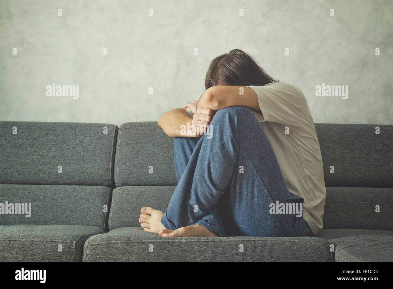 Deprimiert und traurig Mann auf der Couch im Zimmer, bedeckte Gesicht und verzweifelt zu weinen. Stockfoto