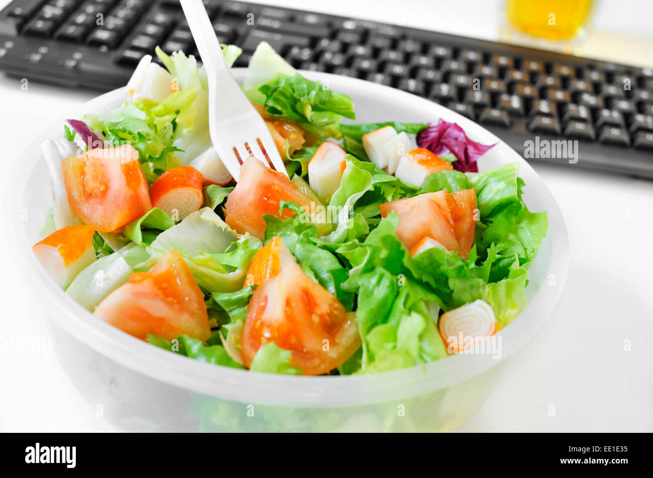 Nahaufnahme von einem Salat in einem Plastikbehälter auf dem Schreibtisch eines Büros Stockfoto