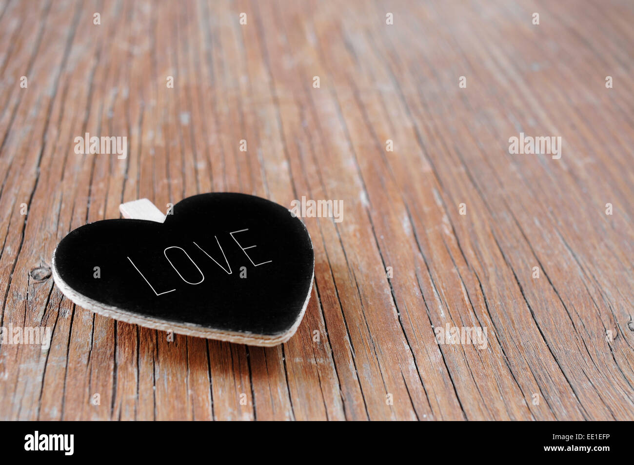 eine Herzform Tafel mit dem Wort Liebe geschrieben auf einer rustikalen Holzoberfläche Stockfoto