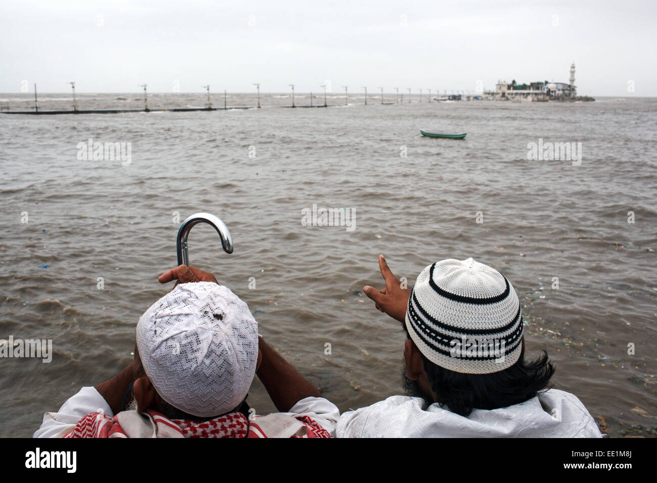 Zwei muslimische Männer schauen Haji Ali Dargah und Moschee mit überfluteten Damm nach starken Regenfällen während der Monsun in Mumbai, Indien Stockfoto