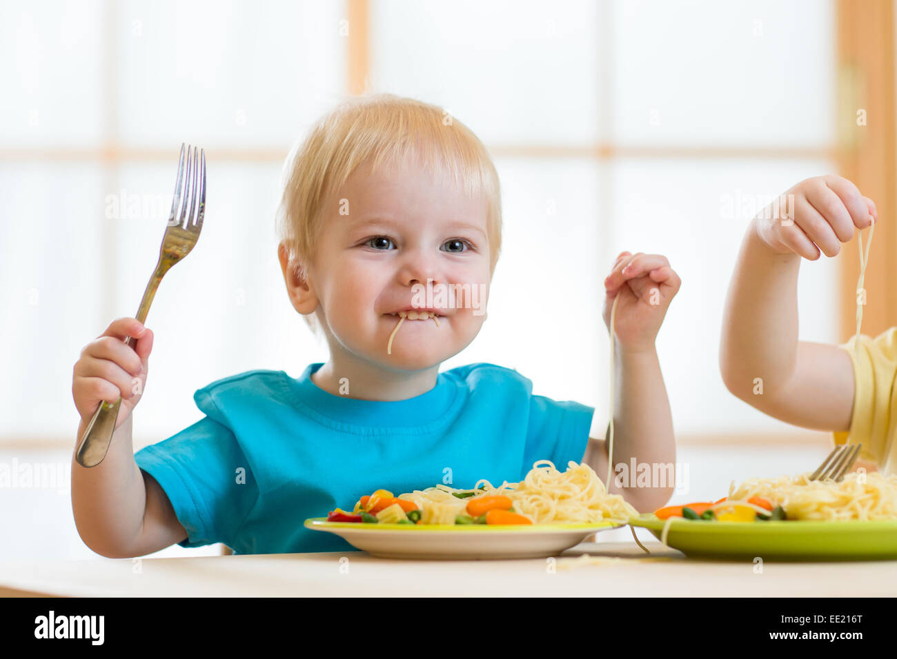 Kinder essen Spaghetti mit Gemüse in Kindergarten Stockfoto