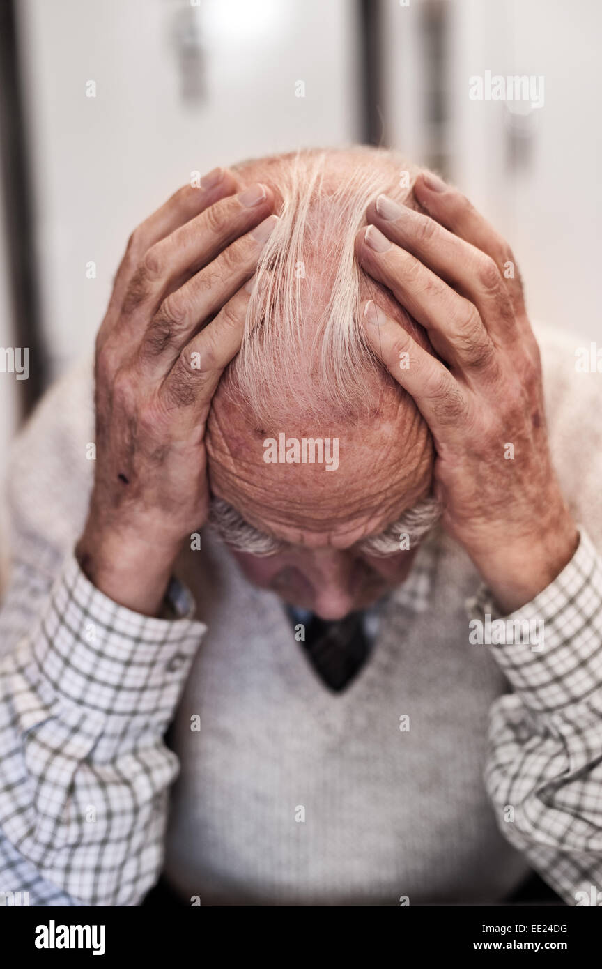 Holding zu den Kopf tief in obwohl sich Gedanken und Betrachtung der Trauer und Glück von früheren Zeiten-Erinnerungen eines Rentners Stockfoto