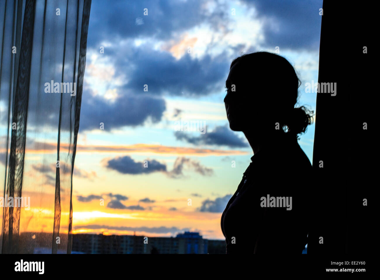 Eine Frau in ihrem Hotelfenster wie die Sonne über Malmö, Schweden. Stockfoto