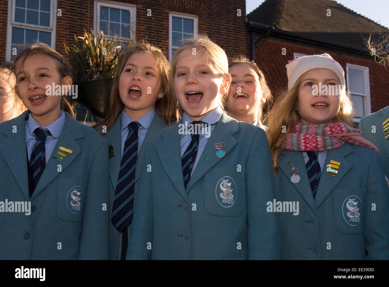 Gruppe der Schulkinder Weihnachten singen Weihnachtslieder auf ein Outdoor-Weihnachtsmarkt, High Street, Haslemere, Surrey, UK. Stockfoto