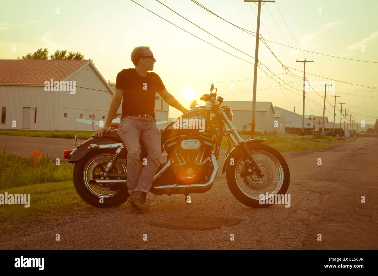 Junge Männer mit seiner Harley Davidson Motorrad wegschauen vor einem schönen Sonnenuntergang in der Sommerzeit Stockfoto