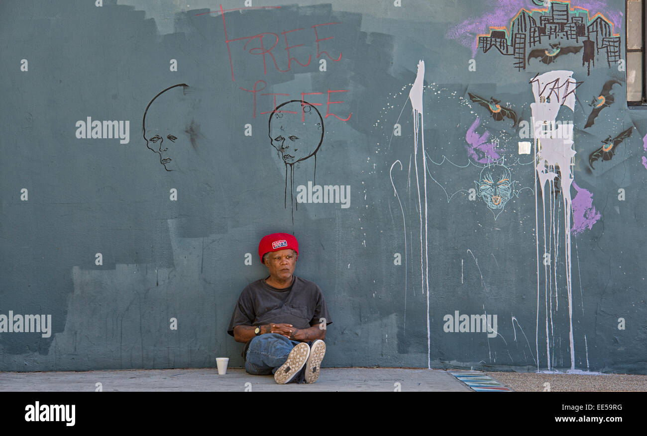 Mann sitzt auf dem Bürgersteig gegen Gebäude, East Village, San Diego, Kalifornien USA Stockfoto