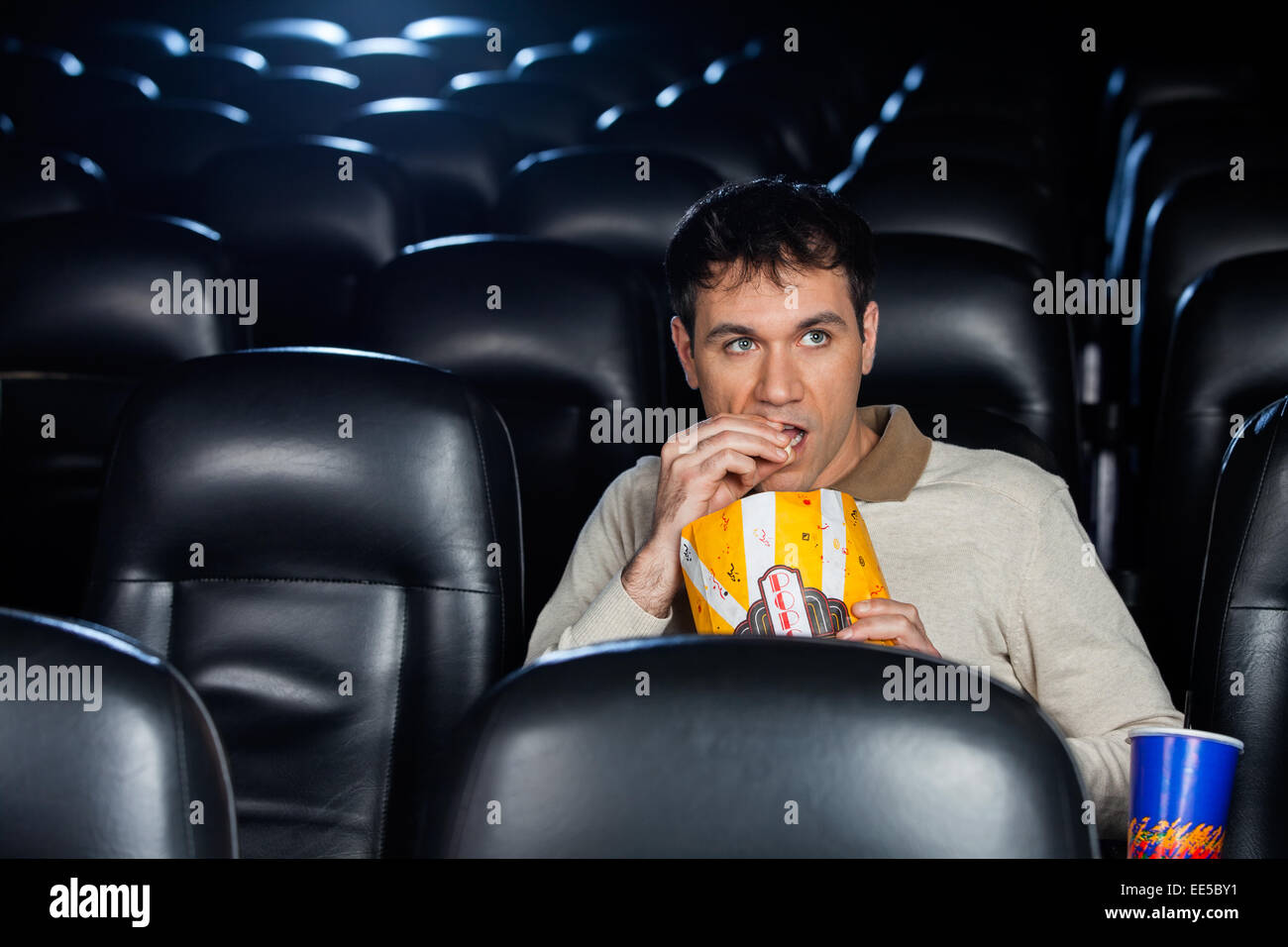 Mann isst Popcorn bei Film im Theater Stockfoto