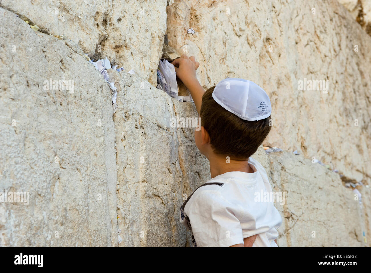 JERUSALEM, ISRAEL - 6. Oktober 2014: Ein kleiner jüdischer Junge ist eine Papier mit einem Wunsch in einen Spalt zwischen den Steinen der westlichen setzen Stockfoto