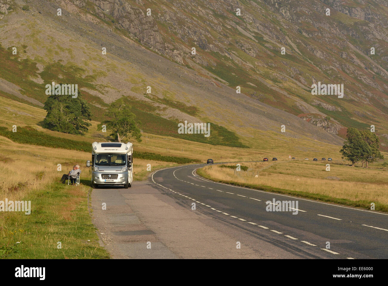 Paar sitzt außerhalb Wohnmobil genießen den Sonnenuntergang von der Seite der Straße - Glencoe, Schottland, Großbritannien Stockfoto