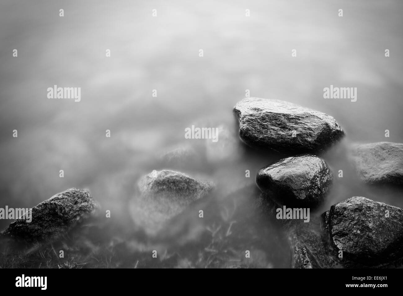 Ruhigen Art Szene mit langer Belichtungszeit von dunklen Felsen und stilles Wasser Stockfoto