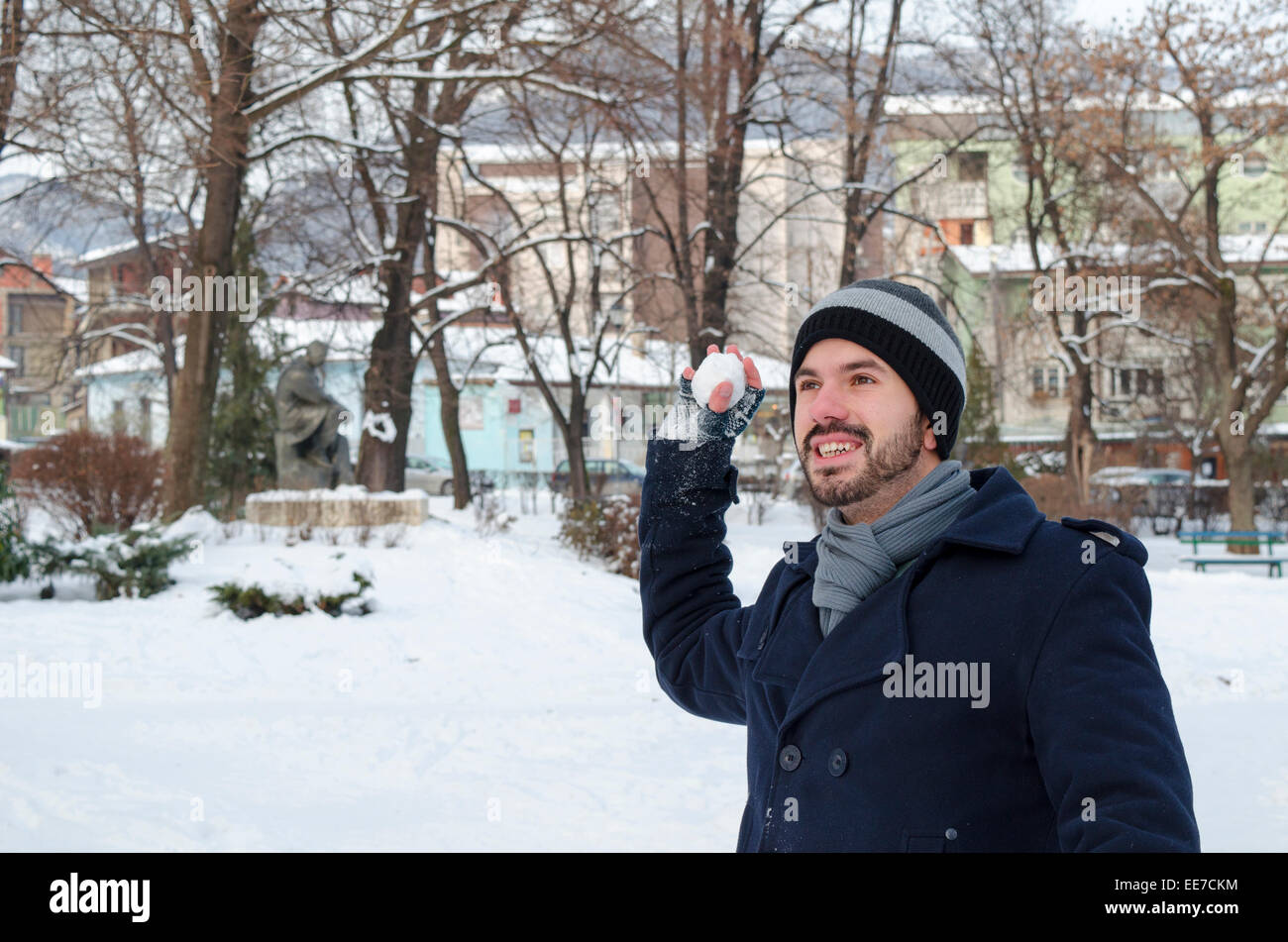 Junger Mann warf einen Schneeball in einem verschneiten park Stockfoto