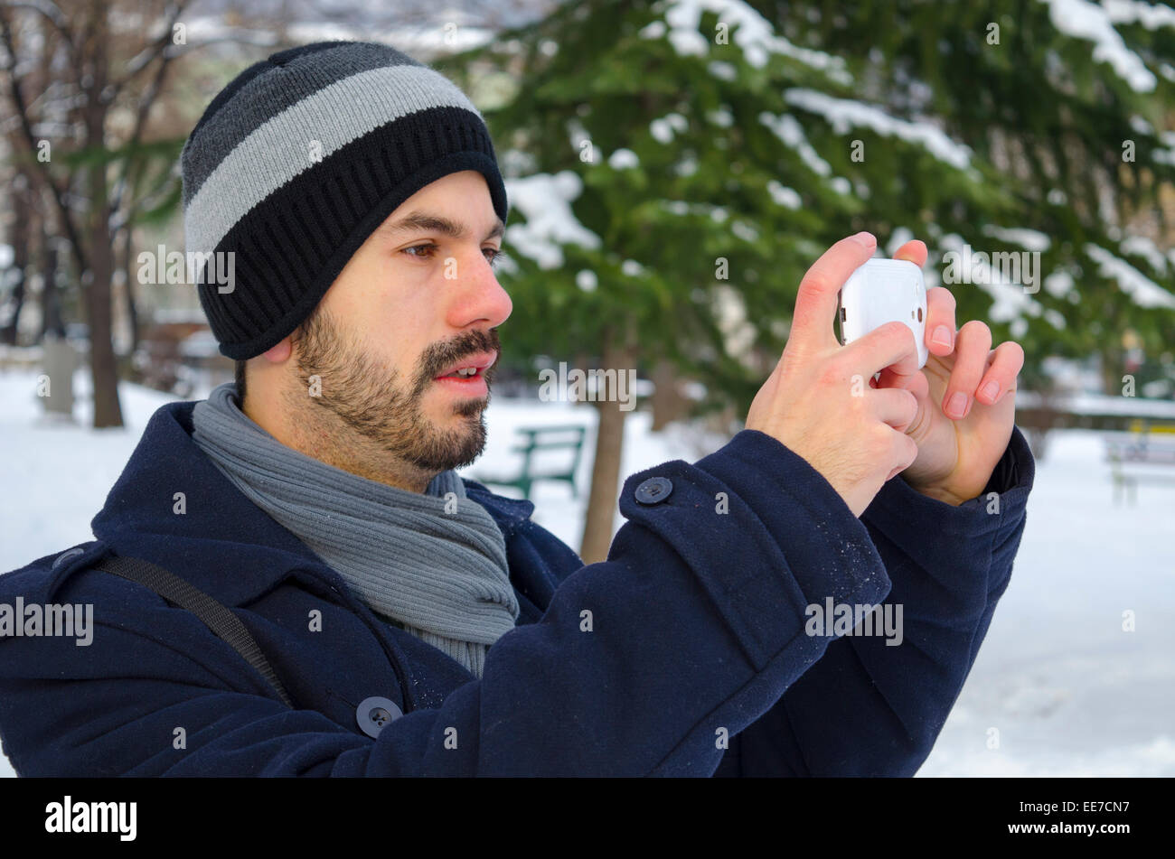 Junger Mann Fotografieren mit seinem Smartphone im winter Stockfoto