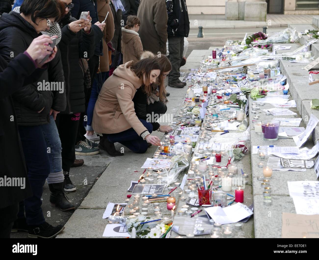 Zwei junge Frauen zünden Kerzen an und Parolen vor Laval Rathaus zu Ehren der Opfer der Zeitschrift Charlie Hebdo. Stockfoto